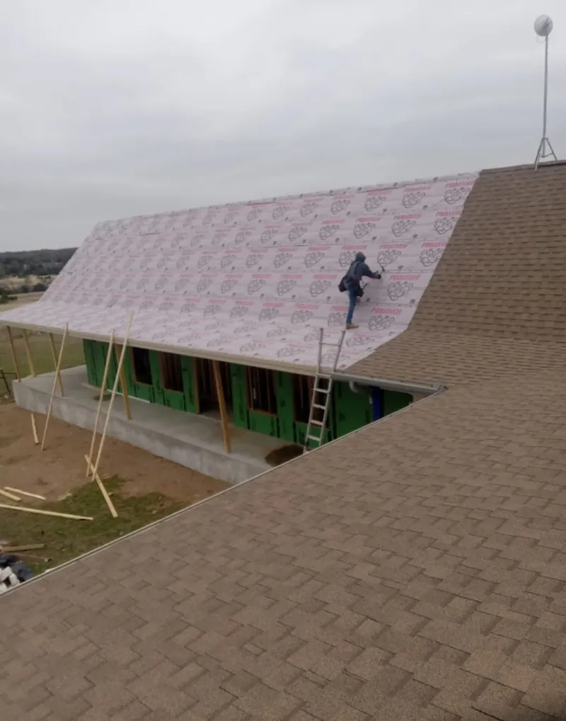 Worker preparing underlayment for a metal roof installation in San Luis